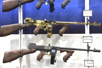 Three tommy guns are hanging on the wall. one is gold, the other two are black.