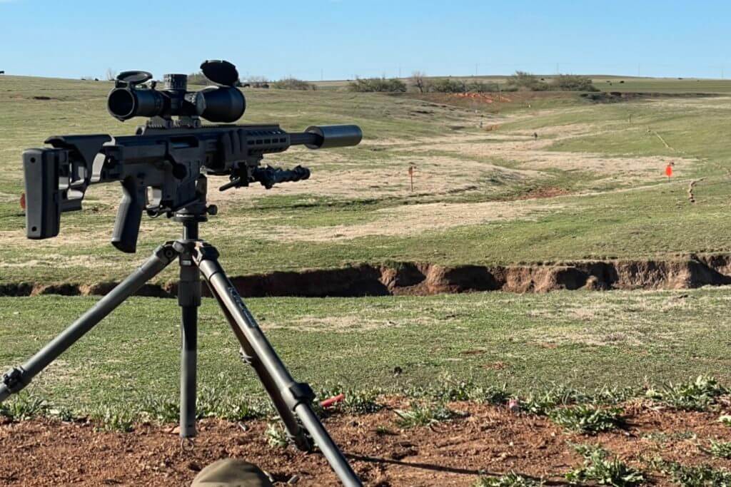 Barrett MRAD sitting in a Kopfjager K800 tripod overlooking a pile of Ta Targets silhouettes at varying distances
