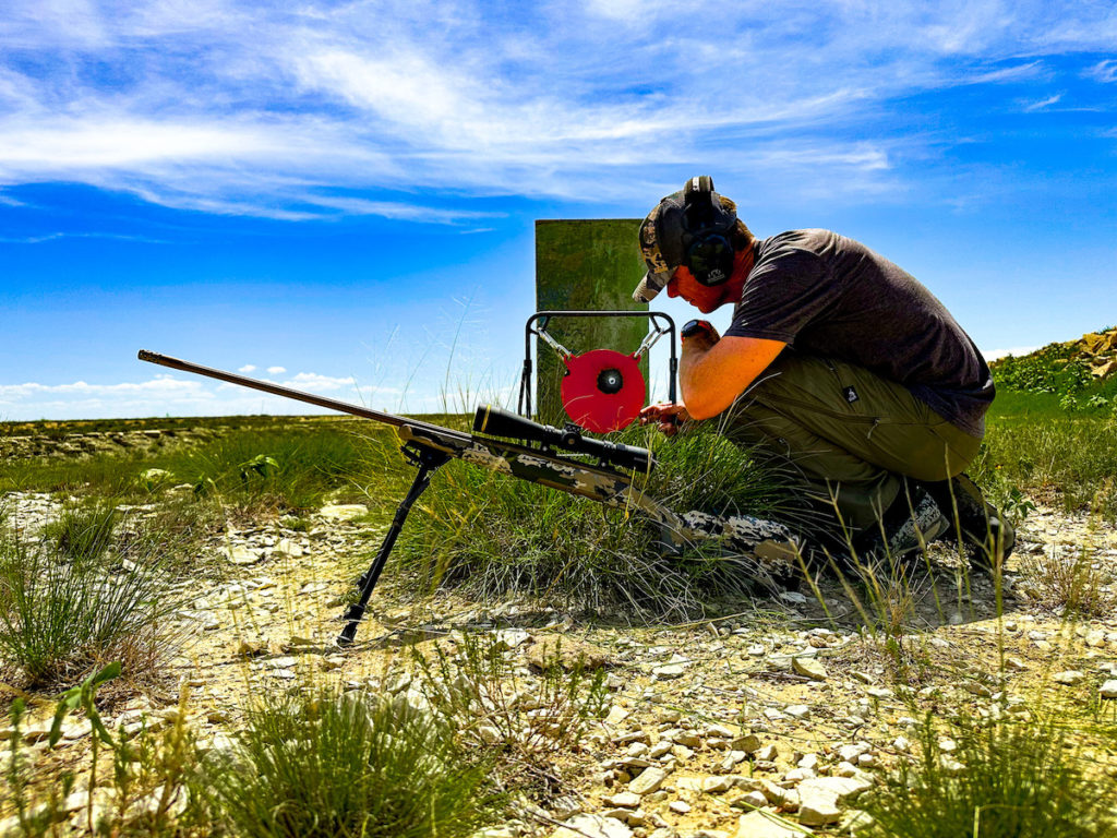 Shooter prepping his 7mm PRC rifle outside under a blue sky